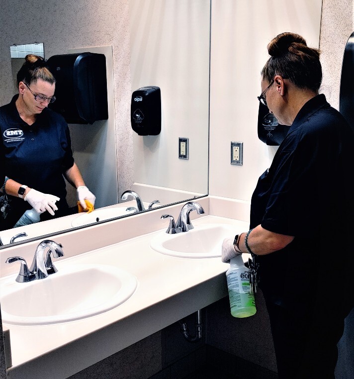 a person smiling while they clean and wipe down a bathroom counter